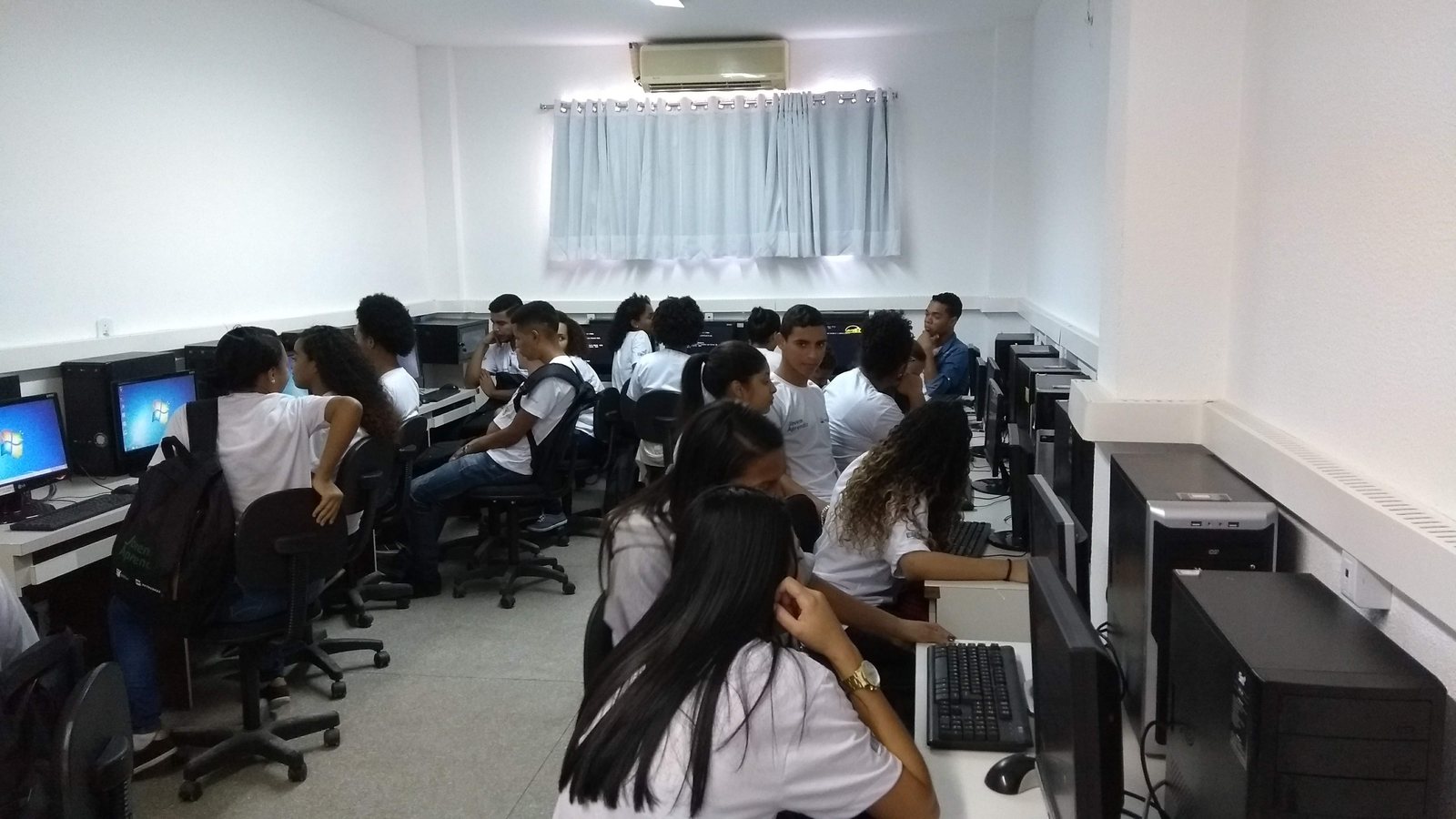 Laboratorio de informatica com alunos usando computadores